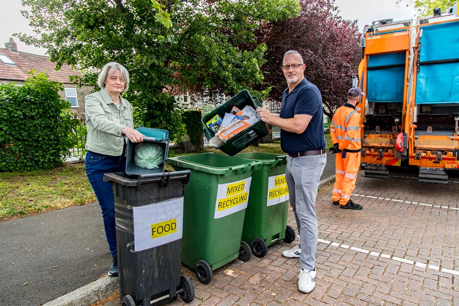 Photo of two councillors emptying recycling containers into bins.