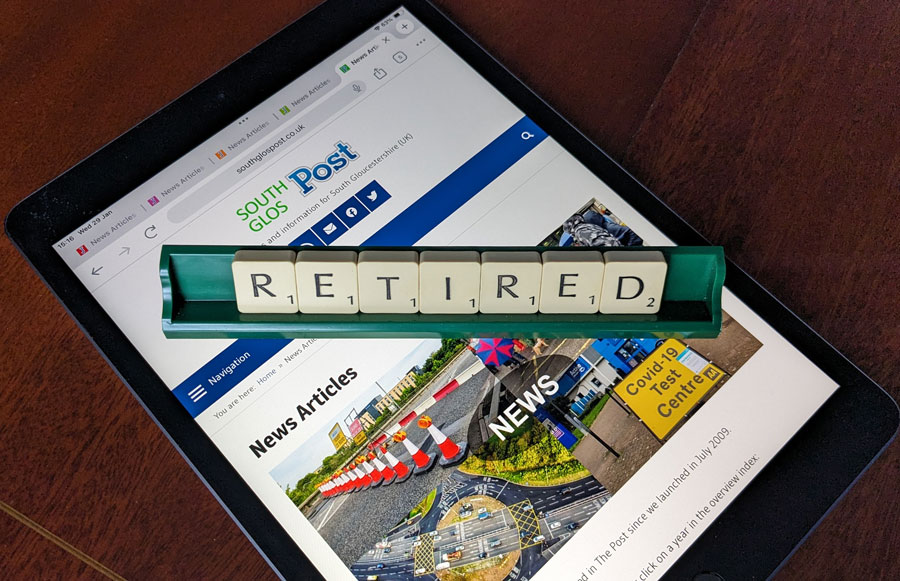 Photo of letter tiles spelling the word 'Retired' in a rack placed over a webpage displayed on an iPad.